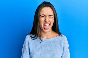 Young hispanic girl wearing casual clothes sticking tongue out happy with funny expression. emotion concept.