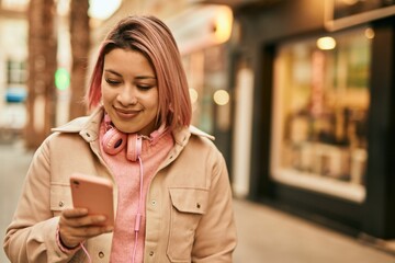 Young hispanic girl using smartphone and headphones at the city.