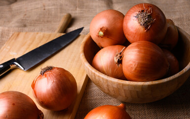 Red and white onions on a wooden chopping board and knife on a rustic wooden table in the kitchen, top view. High quality photo