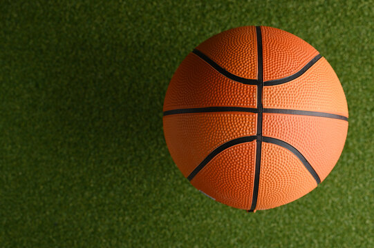 Close-up. Basketball ball on a green basketball court. There are no people in the photo. Minimalism. Professional and amateur sports, outdoor activities, training, advertising.