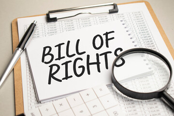 On the table are reports, a magnifying glass, a calculator, and a white notepad with the words BILL OF RIGHTS. Business concept