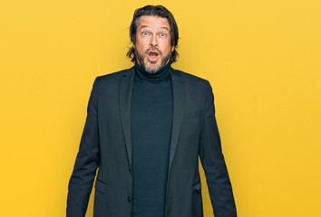 Middle age handsome man wearing business clothes afraid and shocked with surprise expression, fear and excited face.