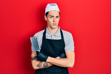 Young hispanic man wearing professional apron holding knife depressed and worry for distress, crying angry and afraid. sad expression.