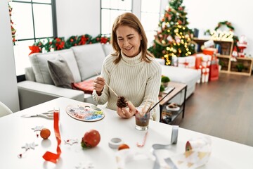 Middle age caucasian woman drawing pineapple to decor christmas tree at home