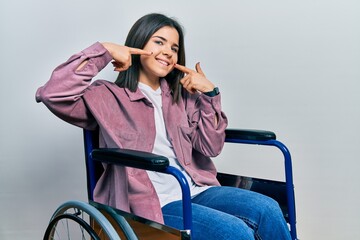 Young brunette woman sitting on wheelchair smiling cheerful showing and pointing with fingers teeth and mouth. dental health concept.