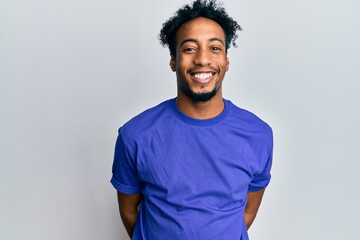Young african american man with beard wearing casual blue t shirt with a happy and cool smile on...