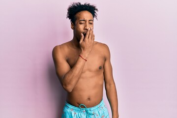 Fototapeta premium Young african american man with beard wearing swimsuit bored yawning tired covering mouth with hand. restless and sleepiness.
