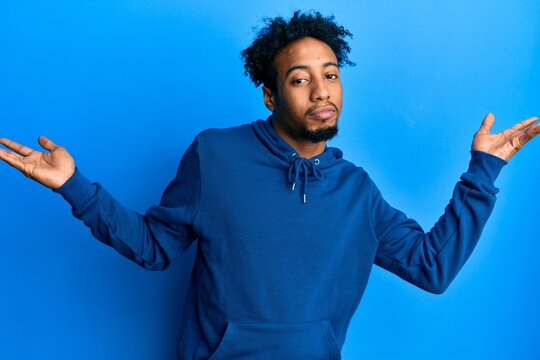 Young african american man with beard wearing casual sweatshirt clueless and confused with open arms, no idea and doubtful face.