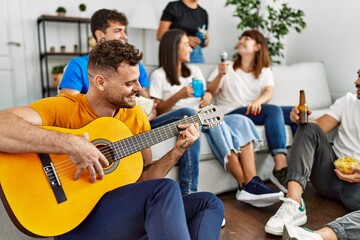 Group of young friends on party smiling happy and playing classical guitar at home.