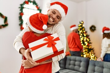 Group of young people on christmas meeting. Couple holding gift and hugging at home.