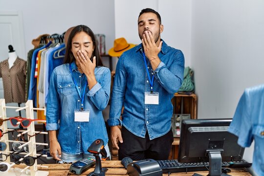 Young interracial people working at retail boutique bored yawning tired covering mouth with hand. restless and sleepiness. - Powered by Adobe