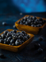 Close-up. Blueberries in square yellow bowls on a dark blue background. Vitamins, fresh juices, dishes from fresh berries, cooking. Culinary blog, recipe book, home cooking.