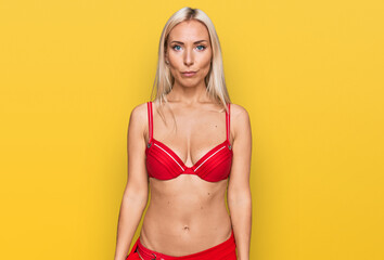 Fototapeta na wymiar Young blonde woman wearing bikini with serious expression on face. simple and natural looking at the camera.