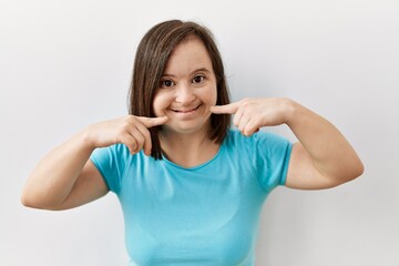 Young down syndrome woman standing over isolated background smiling cheerful showing and pointing...
