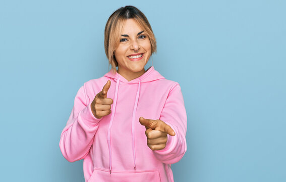 Young caucasian woman wearing casual sweatshirt pointing fingers to camera with happy and funny face. good energy and vibes.