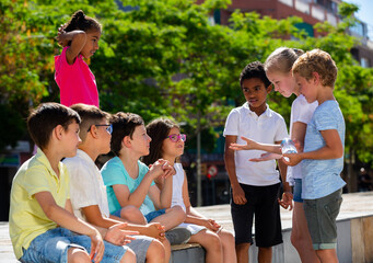 Smiling kids chatting and having fun outdoor in city street together