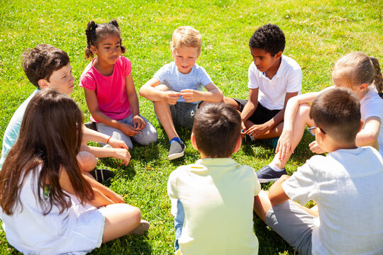 Group of elementary school children chatting on the green lawn. High quality photo
