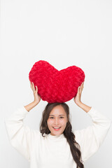 Beautiful Asian woman wearing white sweater holding red heart shape pillow on white background and copy space for Valentine Day concept.