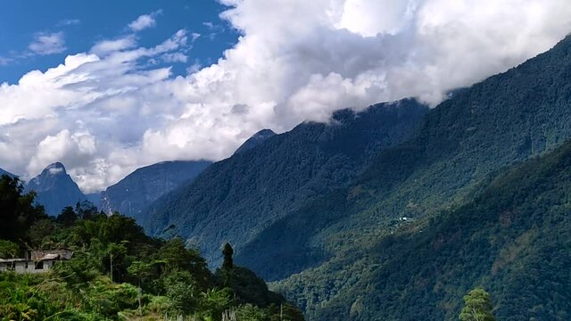 timelapse video of green hills and mountains of himalaya . white clouds drifting in the blue sky.