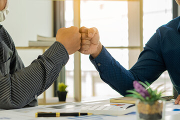 Two young businessmen use fists or punches to punch each other. After completing the agreement in the office Collaboration of colleagues, teamwork concept.