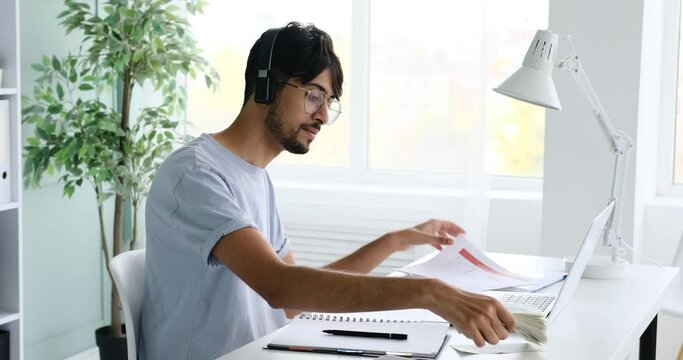 Carefree businessman listening music on headphones and counting money at office