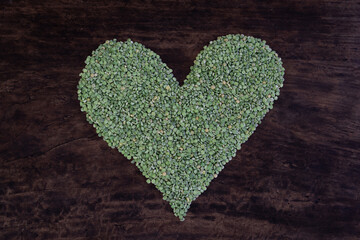 Green heart shape formed with dried split peas on a rustic wooden table