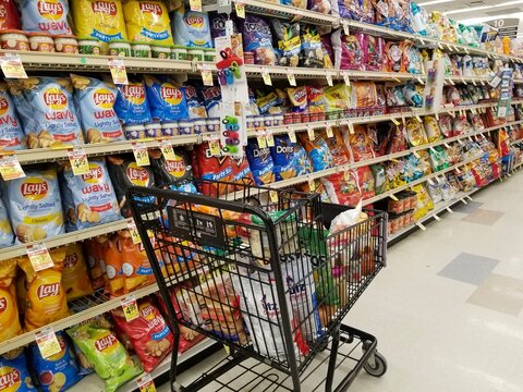 Wilmington, Delaware, U.S.A - January 8, 2022 - A cart filled with groceries on the snacks aisle inside a supermarket