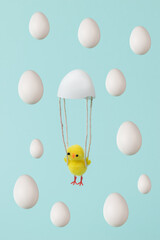 Yellow chicken flying on a parachute from a shell and falling eggs.