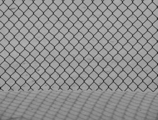 metal chain link school yard fence casting shadows onto snowbank  diamond shapes repeating linked together horizontal black and white image with empty space for type room for type
