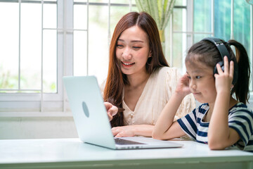 asian mother teach her daughter doing school homework at home. A home schooling concept