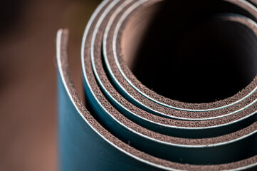 Yoga mat rolled up and standing on end.  Macro view of common home exercise equipment.  Close up of dense foam material, layered and rolled up.  Fitness industry material.