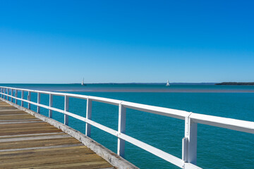 View over the white handrail of Urangan Pier to the blue sea beyond