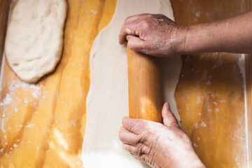 Old woman's hands kneading bread dough. Empanadas. Wooden table.