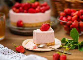A piece of cheesecake lying on a plate next to a cup of sea buckthorn tea on the background of a whole cake