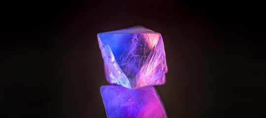 Purple crystals stacked against a black background.  Glowing vibrant semi transparent crystals in wide banner setting with room for text on either side.