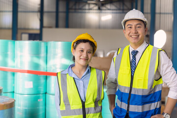 Young engineer working woman standing with adult man worker with safety suit hardhat in factory...