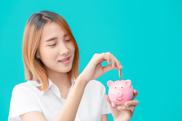 Cute university Asian teen girl happy saving money with smile piggy bank