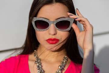 Fototapeta na wymiar Close up portrait of fashionable brunette woman in stylish sunglasses and pink t-shirt.