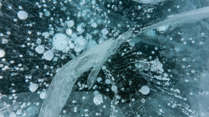 Transparent blue ice. Full screen. Close-up. Deep cracks, bubbles of frozen methane gas are...