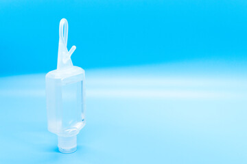 Clear hand sanitizer keychain isolated on a blue background.