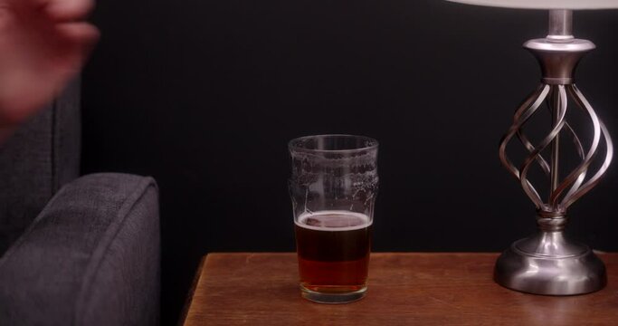 A man grabs a beer off the table to take a drink.