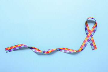 Awareness ribbon on blue background. Concept of autistic disorder - obrazy, fototapety, plakaty