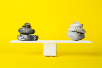 Spa stones on teeterboard against yellow background. Concept of balance