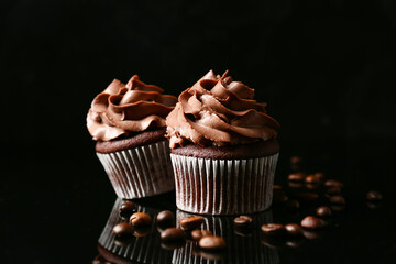 Tasty chocolate cupcakes with coffee beans on dark background