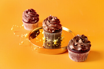 Tasty chocolate cupcakes on orange background