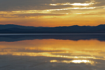 Reflection of the sunset and the mountain in the salt lake