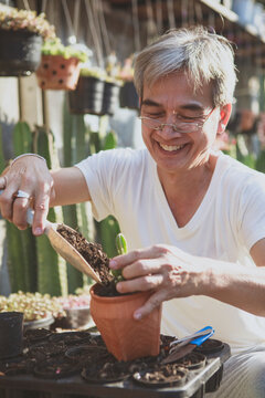 senior asian man smiling with happiness while planting at home garden