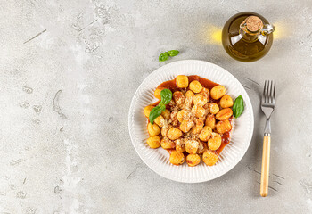 Traditional gnocchi with hot tomato sauce and cheese on a white plate. Potato gnocchi is a very popular Italian food.