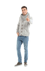 Handsome young man in warm sweater showing thumb-up on white background