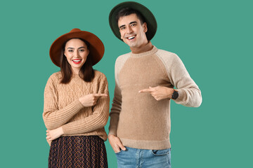 Happy young couple in warm sweaters on color background